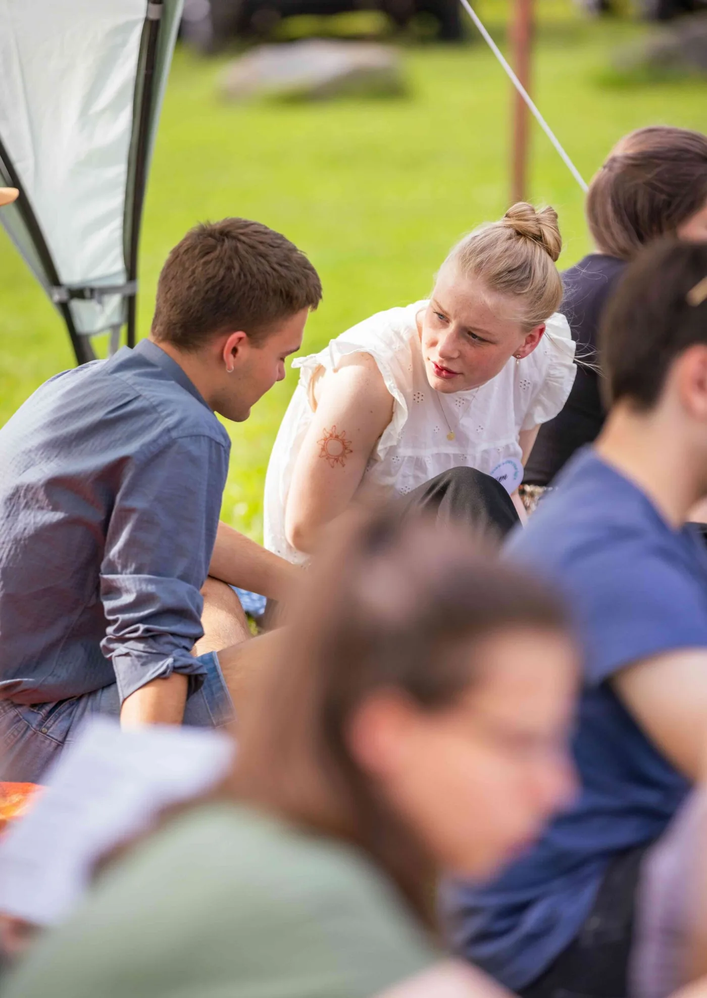 Zwei junge Erwachsene im Gespräch auf einer Wiese